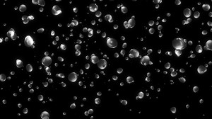 Loop falling down bubble particles animation on black background.