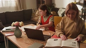 Woman Helping Teen with Homework at Table
