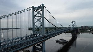 Aerial footage of the Benjamin Franklin Bridge with a cruise ship passing underneath on the Delaware River. The Camden Waterfront is visible in the background.