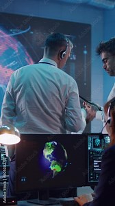 Vertical shot of men pointing at large screen with CO2 emission simulation on Earth and talking about global warming during work in office