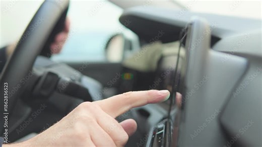 A man works (taps) on a GPS navigation screen on a dashboard in a car - closeup on the device and hand