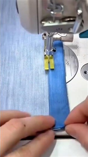 sewing a blue fabric strip precisely using an industrial sewing machine manually