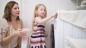 mom and daughter turn on the laundry in the washing machine.