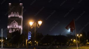 Night view on Hassan tower from the square with lanterns and Flags in Rabat, Morocco. Unfinished mosque minaret overlooking the King Hassan II Mausoleum. Remains of biggest old civilisation in Africa