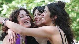Three young women hugging happily in a display of friendship