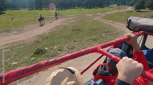First-person view from an SUV driving through the mountains. View of people walking on horseback. There are many people in the interior of the vehicle. Open roof. Off-road travelling