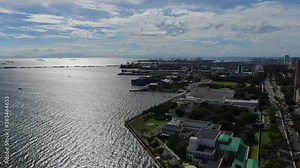 Rotating aerial view of the Roxas boulevard,the wide sea from Manila Bay and the skyline of Manila City.