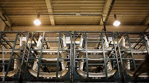 Handheld camera view of an industrial warehouse, rows of neatly stacked car parts, high ceiling with exposed pipes and beams