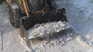 tractor with a bucket collects heaps of snow from the road on a winter . top view. cleaning and removal of snow in the city. consequences of snowfall and storm. clearing snow and ice with a bulldozer