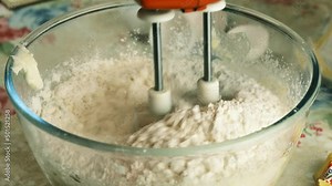 Kneading dough with hand electric mixer. Process of beating the dough using an electric mixer.