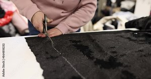 Employee carefully cuts edge of fabric using sharp scissors