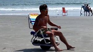 Speed and relaxation unite as beachgoer speeds across the sand on motorized chair