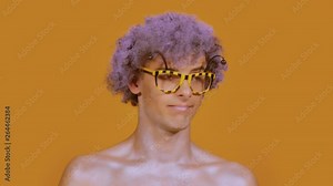 Curly stylish guy in funny glasses waving his head fun on a color orange background. A portrait of a young man looks like a bee or a hornet