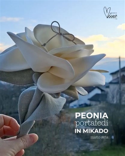 Laura Chierzi _ La Fioraia on Instagram: "Ci sono richieste che arrivano piano e ti cambiano il modo di guardare quello che fai. Questa peonia porta fedi in mikado misto seta è nata da una richiesta di Giovanna. Un dettaglio preciso, pensato con amore: il gambo, perché a portare le fedi sarà una damigella di due anni e mezzo. Un gesto semplice, ma carico di cura. Un modo per rendere quel momento più naturale, più facile, più suo. Io, fino ad ora, i porta fedi li ho sempre realizzati senza gambo.