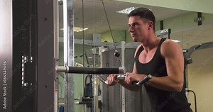 Man in gym doing weight exercise 4k video. Male training arms triceps muscles using cable machine for body mass. Workout bodybuilding sport concept