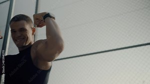 A fit young man displays his muscular biceps in the gym, showcasing strength and determination. Focused Male Athlete Flexing Muscles in Gym during Workout