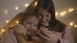 teenage girl with younger sister watching a video in social networks on your smartphone the teen chat room