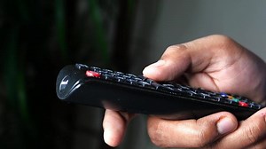 close up of man hand holding tv remote
