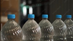 Large automated production robotic conveyor line production drinking products. Pure spring filtered purified carbonated drinking water plastic containers travel one after another along production belt