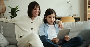 Smiling mother and son utilize a tablet pc for a video call. Their beaming faces and engaging conversation convey warmth and happiness, demonstrating the joy of staying connected through technology.