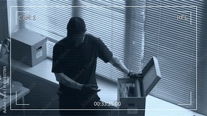 Security camera footage of male criminal hacking into corporate computer in office while partner rummaging through documents in box searching for confidential data during industrial espionage Stock Video