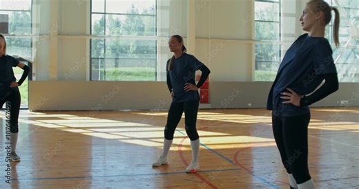 The girls warm up before practice and chat.. Female volleyball players do warm-up exercises before training.
