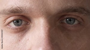 Male gray eyes close-up. The man looks directly into the camera. Slow motion. High quality 4k footage