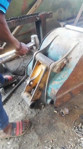TAPPING USING LIGHT HAMMER TO UNSTUCK PIN FROM EXCAVATOR'S END BOSS IN MECHANICAL WORKSHOP