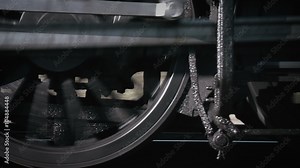 Close-up of steam train wheels moving fast along a track.