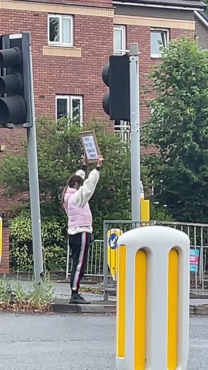 Urban Street Scene: Person Holding Sign at Traffic Island