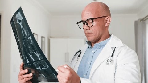 clip-3977281395-focused-doctor-examining-medical-x-ray-scan-pen