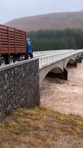 Historic Bridge Fails During Record Floods Inverness, Scotland — October 22, 2024 A massive stone bridge gave way yesterday as torrential rains turned a local river into a violent torrent, nearly swallowing a heavy transport truck in the process. The structure, which had stood for decades, succumbed to the immense pressure of the floodwaters. Dramatic footage captured the exact moment the bridge's central arches failed. A large red truck can be seen cautiously making its way across the span when