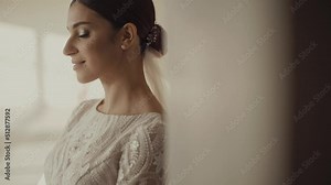 Bride's photo shoot. Portrait of a cute brunette bride. The bride looks out the window and then gently looks into the camera and smiles.