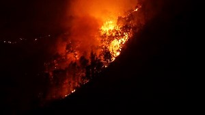 Wide angle shot of wildfire or forest fire burning natural habitat in a hill.