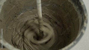 Mixing of dry building mixes with mixers. Wet mortar mixture for finishing work in construction. Close up. cement glue solution or mortar with a drill a bucket with long drill in construction site,