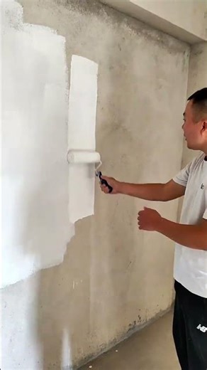 painting interior walls with white paint using a roller on a rough concrete surface area