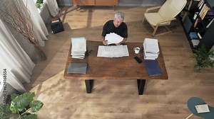 top view of angry man at the desk holding paperwork throw them in air,upset person checking unpaid bills gets furious