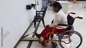 wheelchair patient performing paralyzed foot recovery exercise in physiotherapy session at indoor