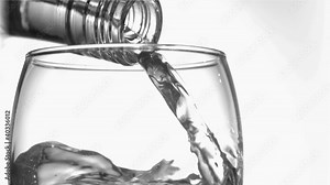 Close up, trickle of water in a super slow motion flowing of the glass bottleneck in a glass