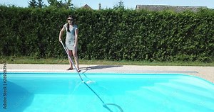 Cleaning the home pool. The woman sucks and cleans the swimming pool. Seasonal work from an aerial perspective.