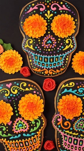 Here is a decorated cookie that I made in honor of Día De Muertos 🇲🇽❤️ I hope you enjoy it! To make this calavera-inspired cookie, I applied a base layer of black flood consistency (15-20 second count) royal icing and let it dry overnight. Then I piped colorful details with medium consistency (soft speak) royal icing. The marigolds are piped with stiff consistency royal icing with a Wilton Cake Decorating tip 59s, which is a small curved petal tip. Once the marigolds were dry, I painted them w