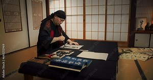 Japanese Male Calligraphy Artist Drawing Artistic Symbols in Kanji Characters. Zen Master or Monk Using an Ink Brush to Practice Traditional Art of Beautiful Writing on Paper