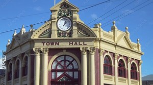 A beautiful, old Town Hall features a clock, intricate patterns, arched windows and cream coloured Ionic style columns which frame brown-red brickwork