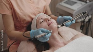 Aesthetician performs a microcurrent facial treatment on a relaxed female client in a professional spa setting, enhancing skin rejuvenation.