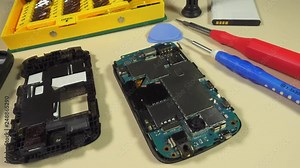 Track over a work bench with the parts of a diassembled mobile telephone being made ready for repair.