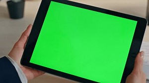 clip-3477451029-businesswoman-hands-holding-greenscreen-tablet-work-desk