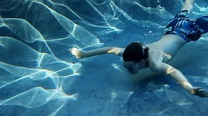 Young boy swimming underwater in a swimming pool. Slow motion conformed from 60 fps.
