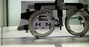 Trial frame and eye chart test on white table. Ophthalmic equipment