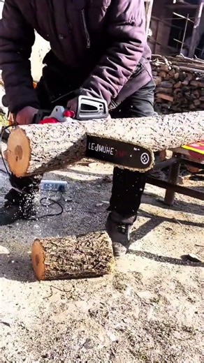 Cutting a large wooden log into smaller pieces using a portable electric chainsaw machine