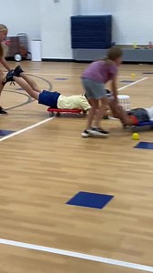 'Hungry Hippo' 🦛 One of my favourite collaborative games that is just such FUN! 🤩 Students have to work together as a team to play in their pairs. One person lies on their stomach on the scooter, while their teammate is behind them, holding up their feet (like a wheelbarrow race, but the scooter is used instead of arms). The person that is behind, pushes the other person’s legs into the middle of the circle so they can catch (i.e. ‘eat’ 😋) objects on the ground with a washing basket. The pair